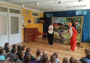 Dzieci siedzą na materacach i oglądają teatrzyk o przyjaźni, na scenie znajdują się aktorzy przebrani za borsuka i liska.