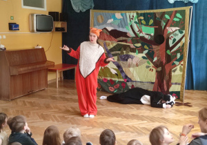 Dzieci siedzą na materacach i oglądają teatrzyk o przyjaźni, na scenie znajdują się aktorzy przebrani za borsuka i liska.