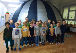Grupa starszaków stoi przed wejściem do namiotu kina sferycznego.