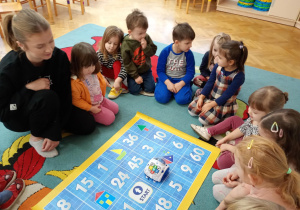 Dzieci obserwują poruszającego się po macie robota.