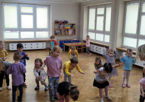 Dzieci wraz z prowadzącą wykonują skłon do przodu.