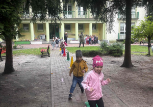 Dzieci wykonują bieg slalomem wokół pachołków.