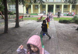 Dzieci wykonują bieg slalomem wokół pachołków.