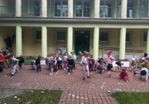 Dzieci ustawione w rzędzie próbują przejść pod liną nie dotykając jej.