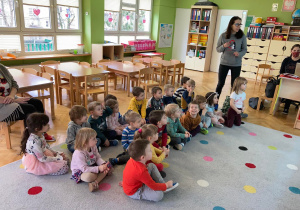 Dzieci siedzą na dywanie oglądając prezentacje o podopiecznych z fundacji tymmmczasy oraz poznając zwyczaje pracy z bezdomnymi zwierzakami.