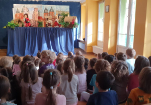 Dzieci siedzą na materacach i oglądają przedstawienie teatrzyku kukiełkowego pt. "Smok wawelski".
