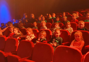 Dzieci siedzą na widowni oglądają spektakl pt. "Słońce Kopernika".