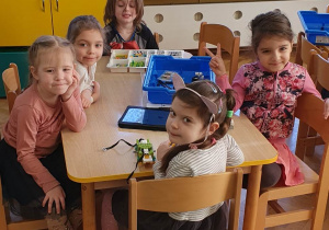 Dzieci siedzą przy stoliku i budują swojego robocika z klocków LEGO.