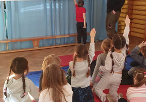 Dzieci siedzą na materacach, na rzutniku wyświetlana jest prezentacja nt. mostów, a jeden z chłopców wskazuje na jedno ze zdjęć.