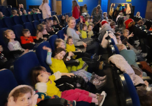 Dzieci siedzą na fotelach w kinie i czekają na rozpoczęcie seansu filmowego.