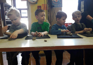 Chłopcy siedzą przy stoliku i lepią z gliny na warsztatach ceramicznych w pracowni ceramicznej Amfora.