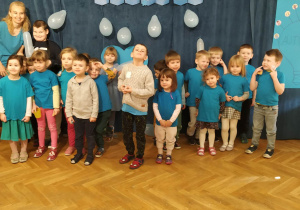 Dzieci ubrane na niebiesko pozują do grupowego zdjęcia na tle napisu "Dzień świadomości autyzmu".