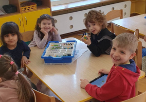 Dzieci siedzą przy stoliku i prezentują zbudowany samolot z klocków Lego na zajęciach z robotyki i programowania.