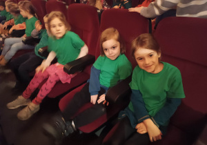 Dzieci siedzą na fotelach w kinie i czekają na początek filmu.