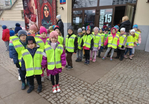 Dzieci ubrane w kamizelki odblaskowe stoją przed wejściem do kina Muranów.