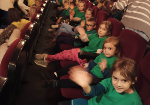 Dzieci siedzą na fotelach w kinie i czekają na początek filmu.