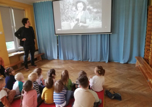 Dzieci siedzą na materacach i oglądają prezentację nt. kina niemego.