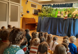 Dzieci siedzą na materacach i ławkach i oglądają teatrzyk kukiełkowy pt. "Kwiat paproci".