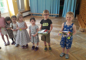 Dzieci stoją i prezentują swoje nagrody zdobyte w konkursie plastyczny pt. "Wiosenna łąka".