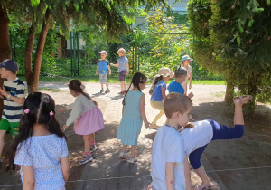 Dzieci pokonują tor przeszkód przechodząc przez liny z nogami wysoko uniesionymi.