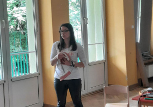 Dzieci siedzą na materacach, a prowadząca warsztaty stomatologiczne prezentuje im model ludzkiej szczęki.