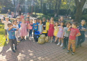 Dzieci z grupy stoją za koszami do recyklingu i wskazują ile śmieci oraz liści udało im się zebrać w ramach akcji ,,Sprzątania Świata".