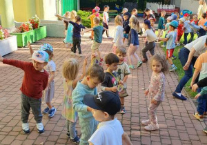 Przedszkolaki tańczą do piosenki pt. ,,Mucha w mucholocie", rozkładają ramiona jakby leciały w samolocie.
