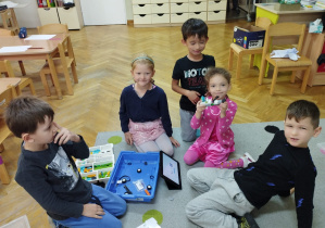 Trzech chłopców i dwie dziewczynki prezentują wykonanego przez siebie robota.