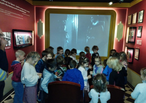 Dzieci zajmują miejsca w sali kinowej muzeum, będą oglądać film bez kolorów i głosów.