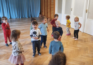 Dzieci z rączkami na bioderkach tańczą w rytm muzyki.