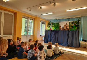 Dzieci przyglądają się scenografii ukazującej kościół Mariacki w Krakowie.