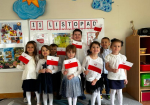 Dzieci z oddziału II pozują w swojej sali do pamiątkowego zdjęcia trzymając w dłoniach flagi.