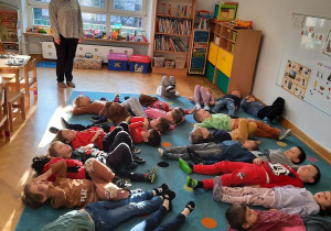 Dzieci leżą na dywanie i utrwalają prawidłowy tor oddechowy.