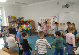 Dzieci tańczą w kole trzymając się za łapki swoich misiów.
