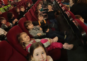 Dzieci z oddziału III siedzą na fotelach w sali kinowej.