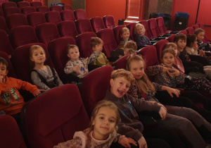 Dzieci z oddziału IV siedzą na fotelach w sali kinowej.