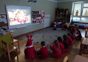 Przedszkolaki oglądają na tablicy interaktywnej historię o św. Mikołaju.