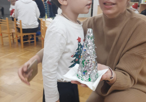 Chłopczyk wraz z mamą prezentują wykonaną ozdobę świąteczną.