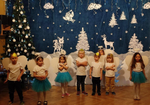 Cztery dziewczynki i czterech chłopców przebranych za aniołki i gwiazdeczki stoi na środku sali gimnastycznej.