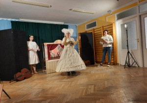 Jedna z nauczycielek występuje w roli narratora, który opisuje rolę odgrywaną przez operową diwę stojącą na środku sali.