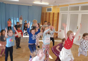 Dzieci podskakują jak najwyżej potrafią ilustrując układ taneczny.