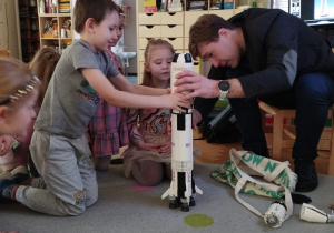 Chłopiec pomaga w zbudowaniu modelu rakiety kosmicznej z części.