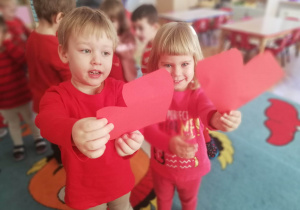 Chłopczyk i dziewczynka pokazują identyczne czerwone serduszka.