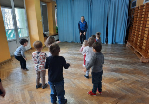 Prowadząca stoi na środku sali i wystukuje rytm o uda, dzieci stojące naprzeciwko powtarzają pokazywane przez nią ruchy.