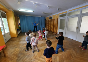 Dzieci poruszają bioderkami do muzyki, a uniesionymi rączkami poruszają na boki.