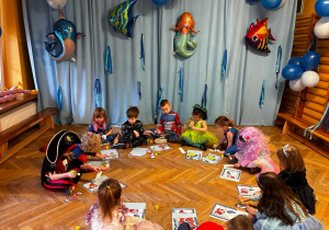 Dzieci z oddziału II siedzą w kółeczku i układają puzzle przedstawiające morskich bohaterów bajek.