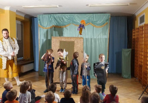Pięciu chłopców stoi na środku sali w ręku trzymając rekwizyty: konia na patyku, tarczę lub halabardę.