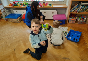 Chłopczyk trzyma w ręku gotowego robota "słonika", którego zbudował wspólnie z kolegą.