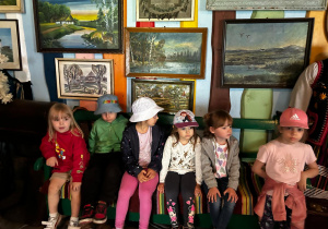 Dzieci oglądają wnętrze chaty gościnnej.