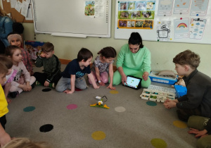 Dzieci wraz z prowadzącą programują robota.
